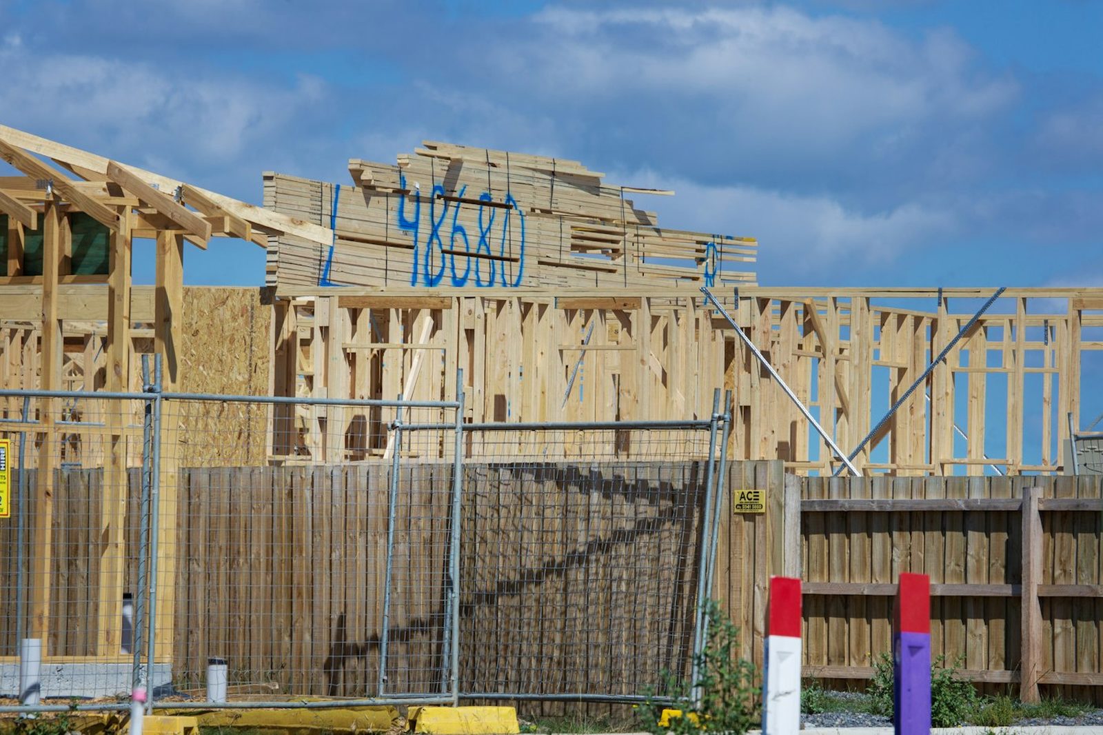 Timber-framed walls and roof structure of a house under construction, seen from the street