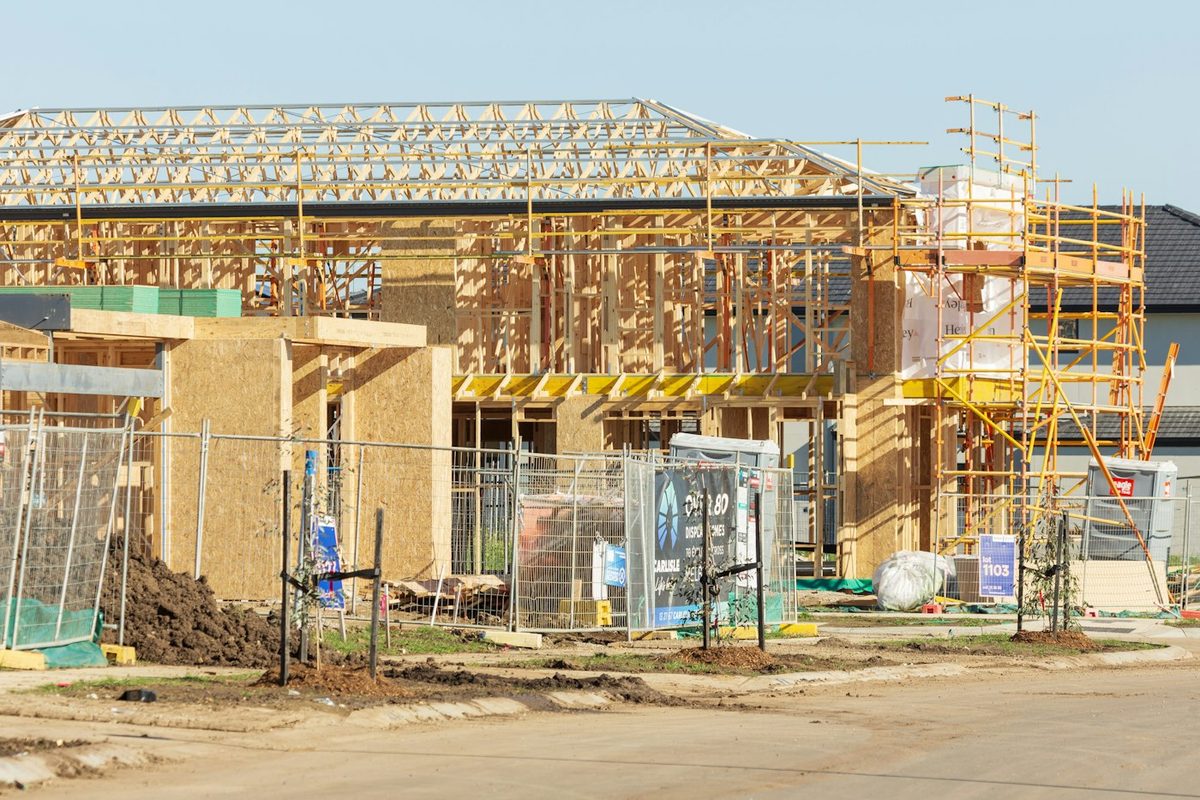 Timber-framed house under construction with scaffolding across the front elevation