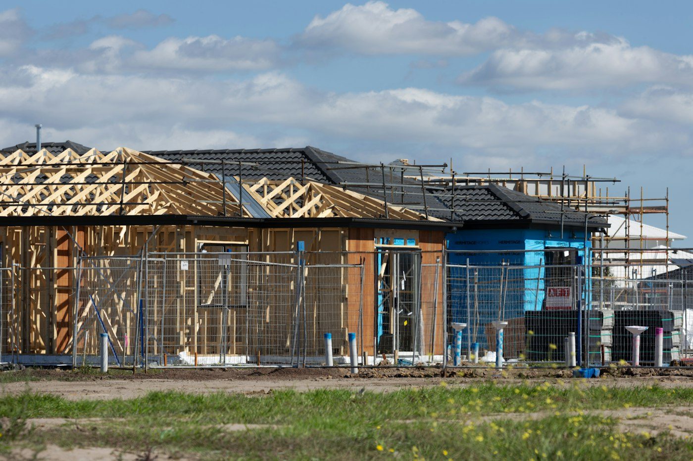 Timber-framed house under construction with scaffolding along both elevations